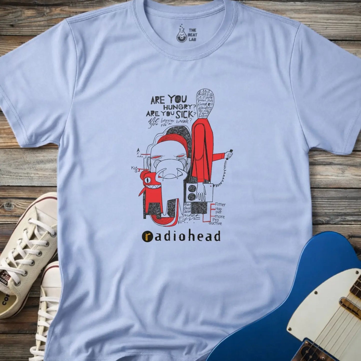 Light blue color adult unisex t-shirt gildan 64000  Radiohead comic sketch t-shirt with abstract cartoon figures in red/black line art and ‘Are you hungry? Are you sick?’ text above stylized band name.