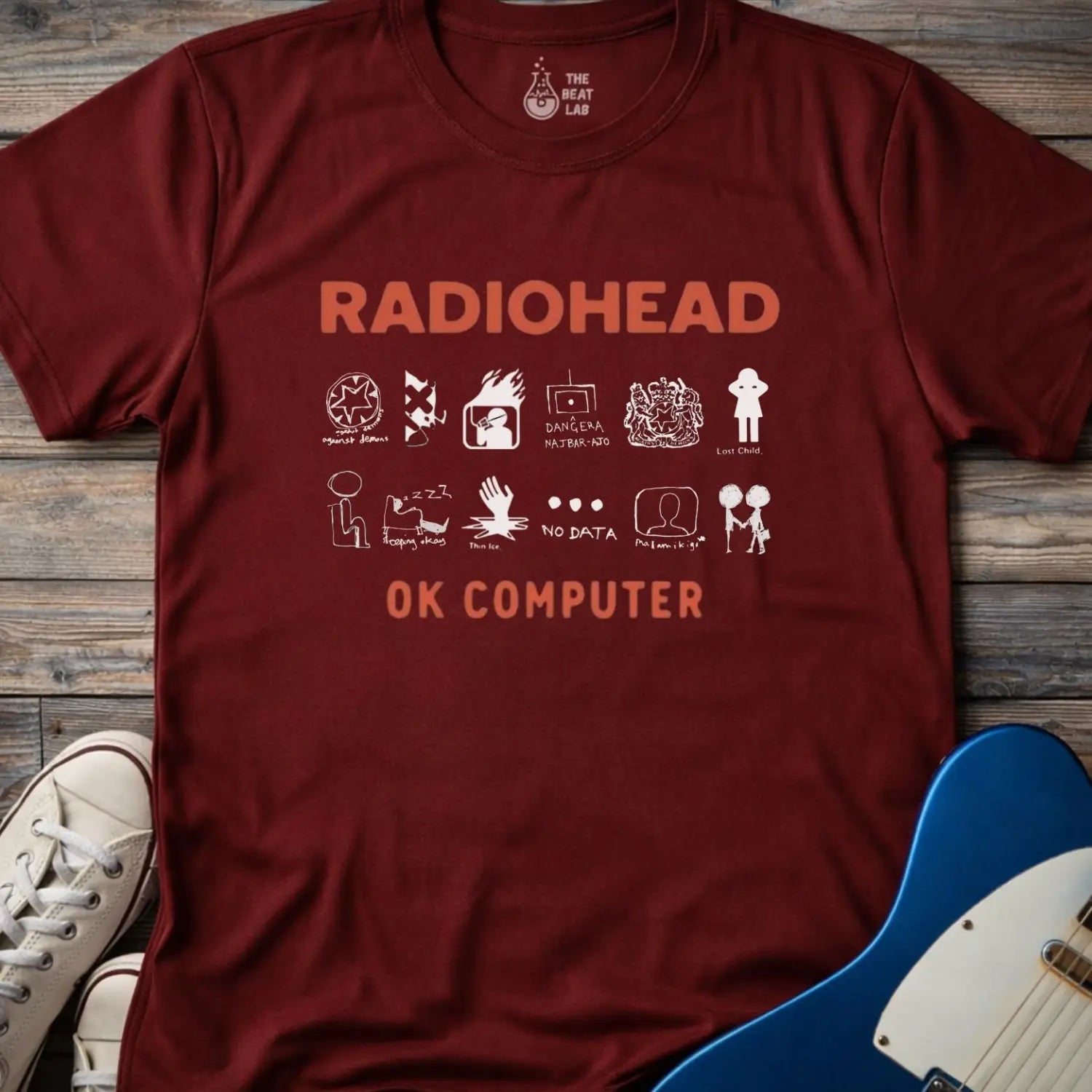 Maroon red color adult unisex t-shirt gildan 64000 Radiohead OK Computer graphic t-shirt with large RADIOHEAD and OK COMPUTER text and a horizontal row of minimalist white icons in between.