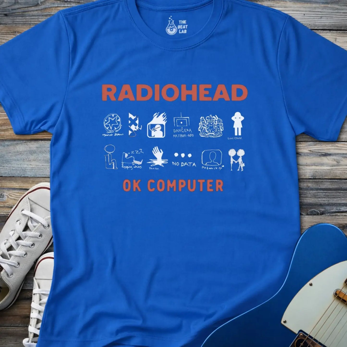 Royal blue color adult unisex t-shirt gildan 64000 Radiohead OK Computer graphic t-shirt with large RADIOHEAD and OK COMPUTER text and a horizontal row of minimalist white icons in between.