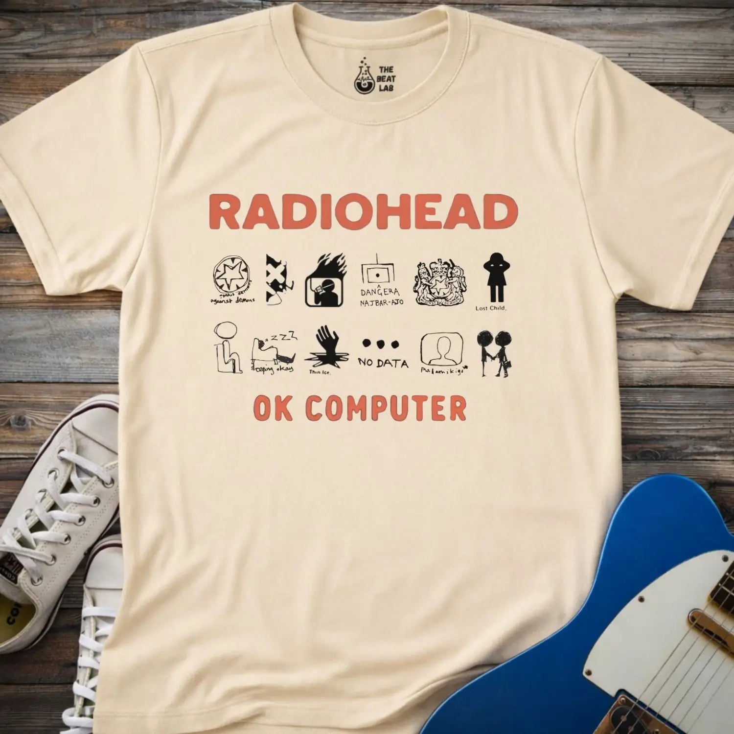 Sand beige color adult unisex t-shirt gildan 64000 Radiohead OK Computer graphic t-shirt with large RADIOHEAD and OK COMPUTER text and a horizontal row of minimalist white icons in between.