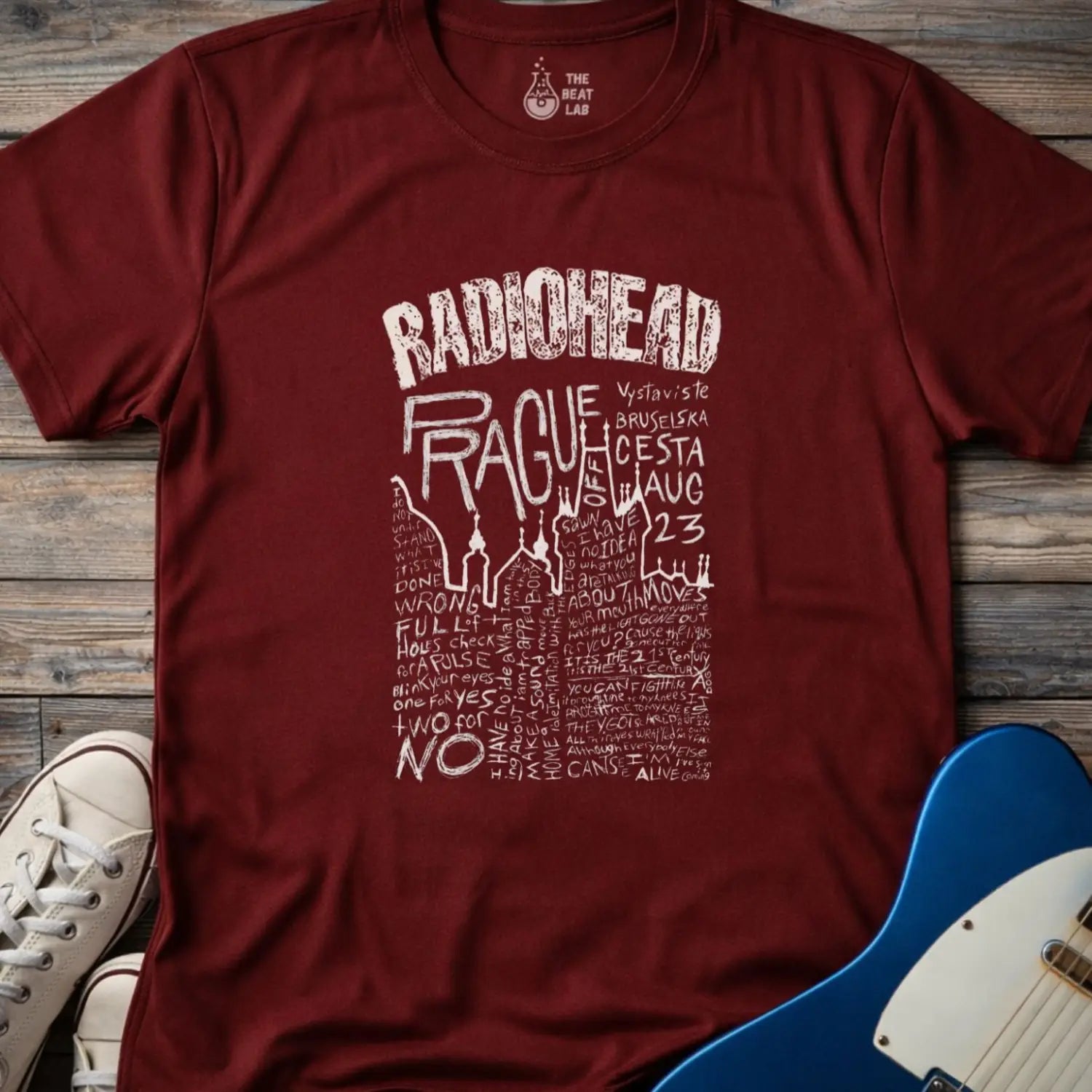 Maroon color adult unisex t-shirt gildan 64000 Radiohead Prague concert graphic t-shirt with distressed RADIOHEAD header, large hand-drawn PRAGUE text, date details, and dense handwritten lyric-style lettering.