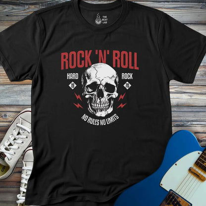 The Rock 'N' Roll 1970 T-shirt is black with a large skull graphic, bold red ROCK N ROLL text, and the phrases HARD ROCK 1970 and NO RULES NO LIMITS. Displayed on a wooden surface with white sneakers and a blue electric guitar nearby.