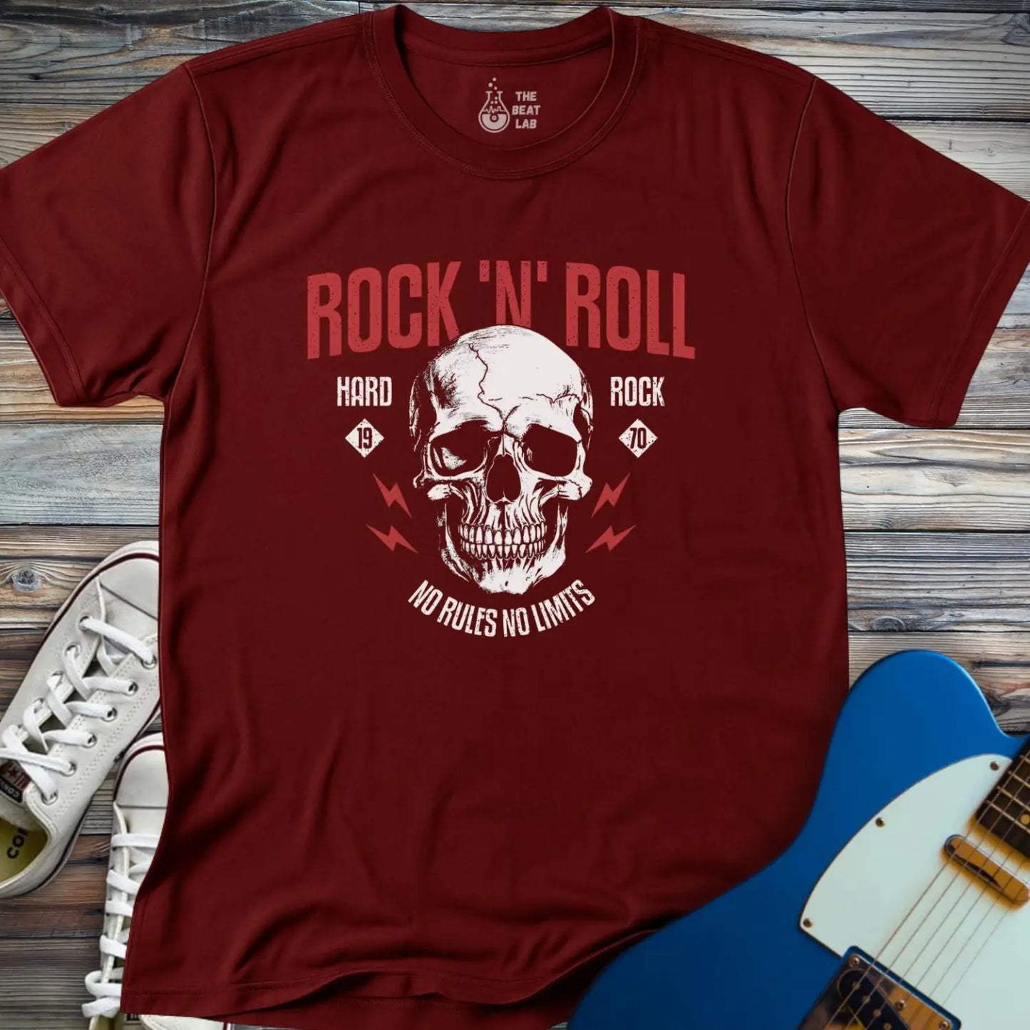 The Rock 'N' Roll 1970 T-shirt features a maroon color, a large skull graphic with the text "Rock N Roll, Hard Rock, No Rules No Limits," plus a guitar and white sneakers on a wooden background.