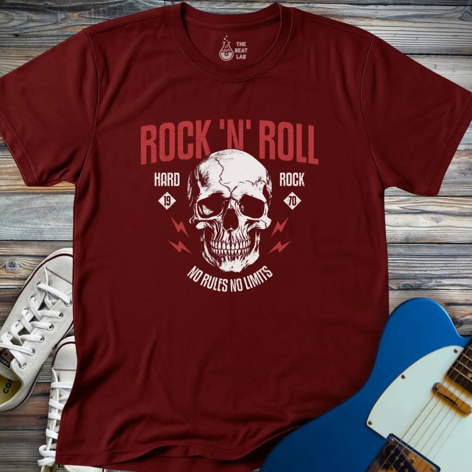The Rock 'N' Roll 1970 T-shirt features a maroon color, a large skull graphic with the text "Rock N Roll, Hard Rock, No Rules No Limits," plus a guitar and white sneakers on a wooden background.