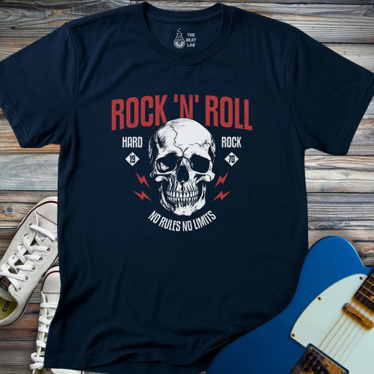 The Rock 'N' Roll 1970 T-shirt is a navy blue tee with a white skull, red lightning bolts, and “ROCK ‘N’ ROLL,” “HARD ROCK,” and “NO RULES NO LIMITS” text, shown beside white sneakers and a blue electric guitar on wood.