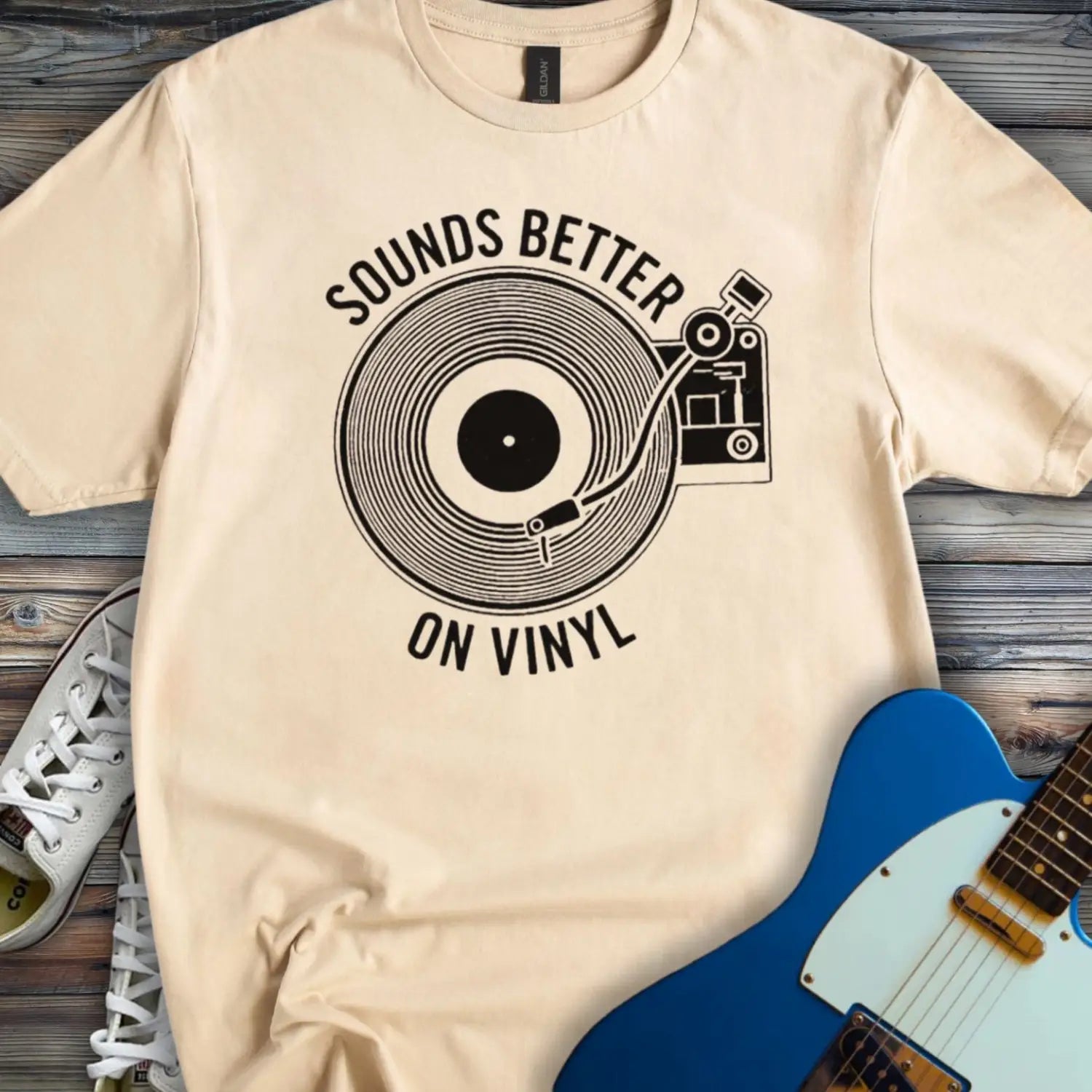 Sand color of graphic t-shirt with white vinyl record player design and “Sounds Better on Vinyl” music slogan for retro music lovers.
