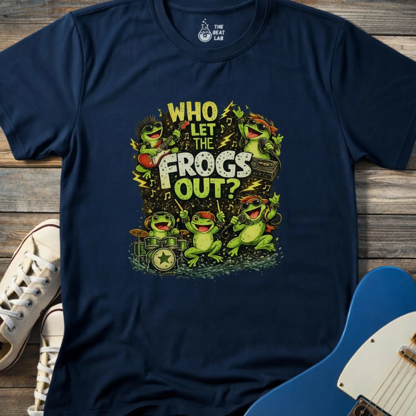 Navy blue adultt men women gildan 64000 shirt featuring Cartoon frog rock band graphic with text “Who Let The Frogs Out?” featuring guitarist, drummer, and singers with lightning bolts and music notes